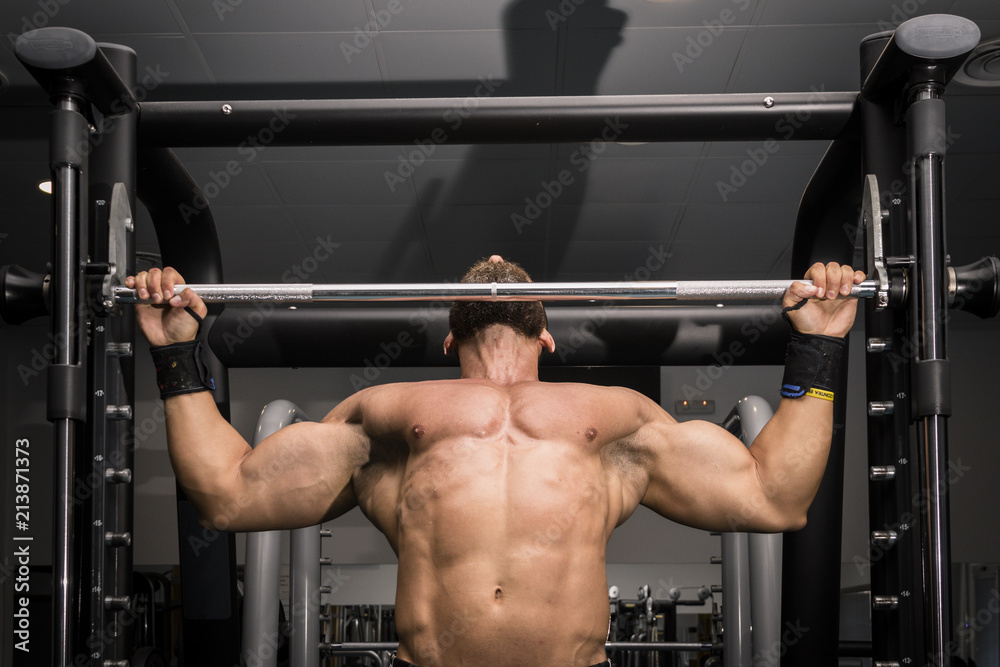 Stockfoto Hombre fuerte con grandes musculos haciendo dominadas en el gimnasio. Ponerse en forma. Adobe Stock