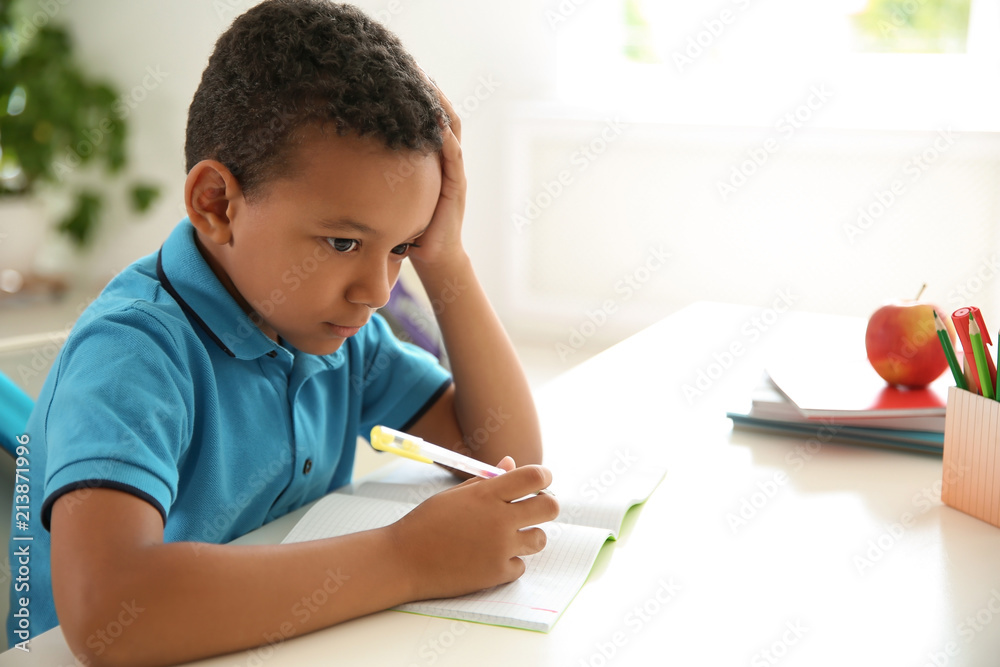 Cute little child doing assignment at desk in classroom. Elementary school Cute little child doing assignment at desk in classroom. Elementary school