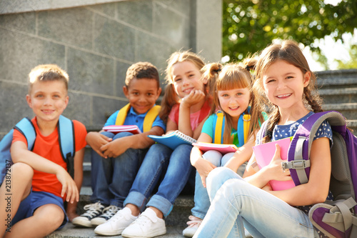 Cute little children with backpacks and notebooks outdoors. Elementary school