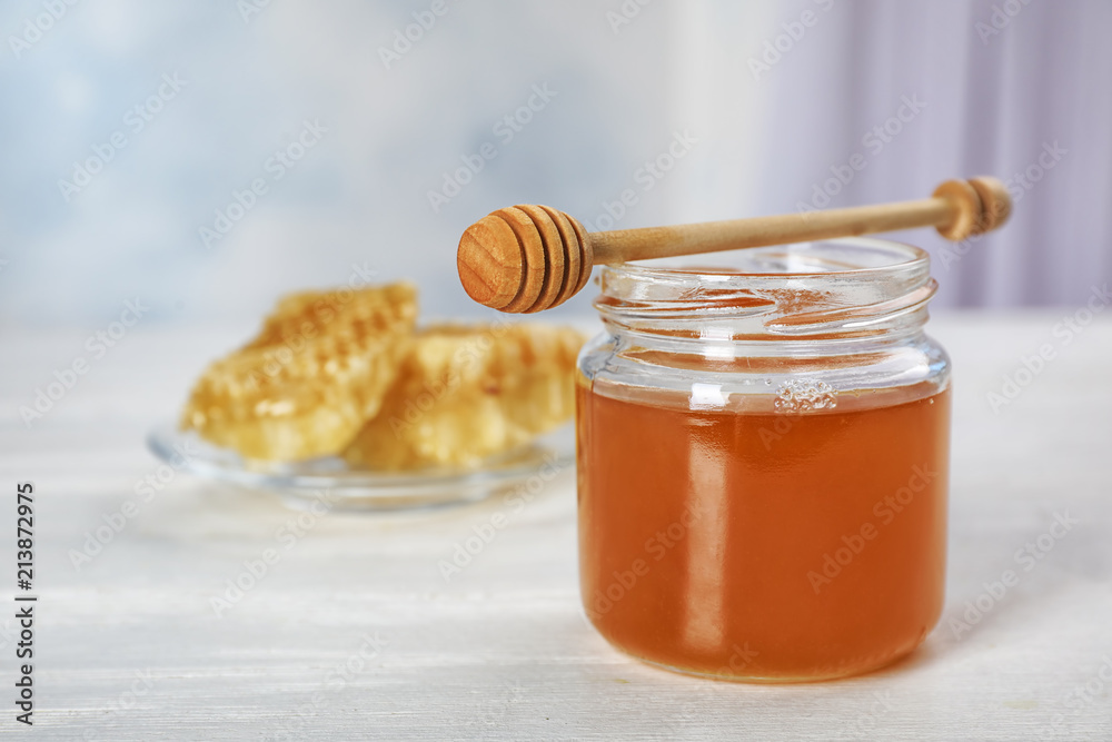 Jar of honey and dipper on table Jar of honey and dipper on table