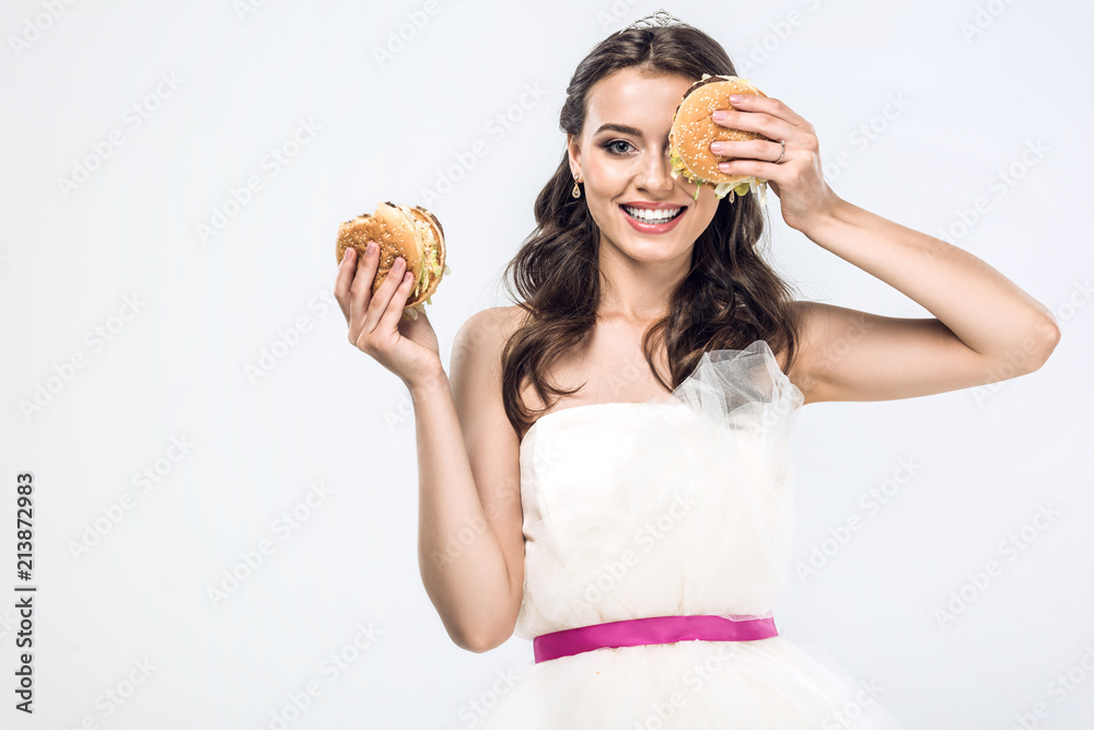 smiling young bride in wedding dress holding burgers in hands isolated on white smiling young bride in wedding dress holding burgers in hands isolated on white