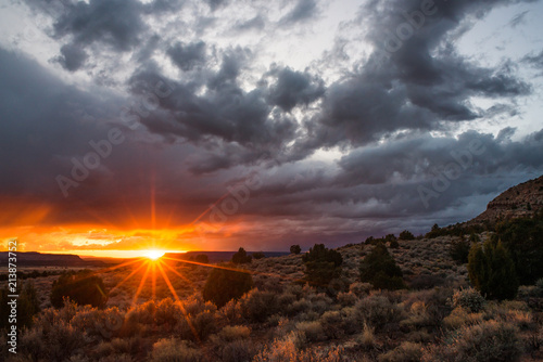 Sunset peeking through the storm over desert wilderness; Southern Utah