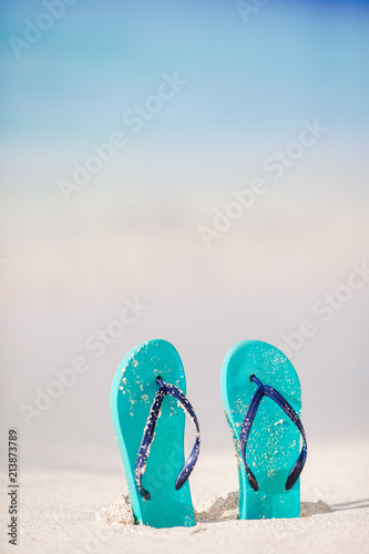 Summer mint flip flops with sunglasses on white beach