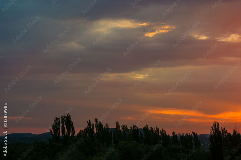 Landscape with dramatic light - beautiful golden sunset with saturated sky and clouds.