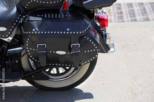 Close up of a black leather strapped and studded motorcycle pannier or bag, on a sunny day photo