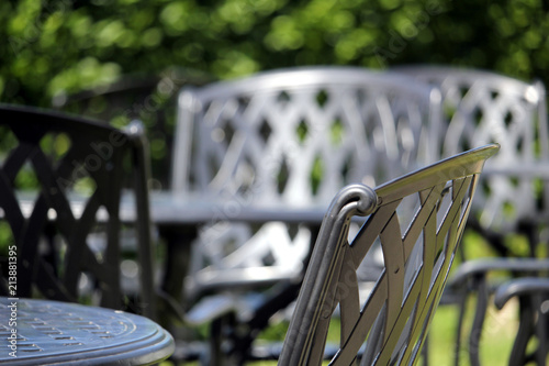 Close up of a wrought iron chair, with other similar chairs and tables in the out of focus background on a lovely sunny day photo