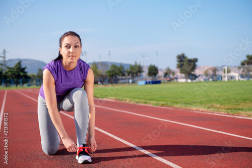 Young woman runner tying shoelaces. Exercise concept. © blicsejo