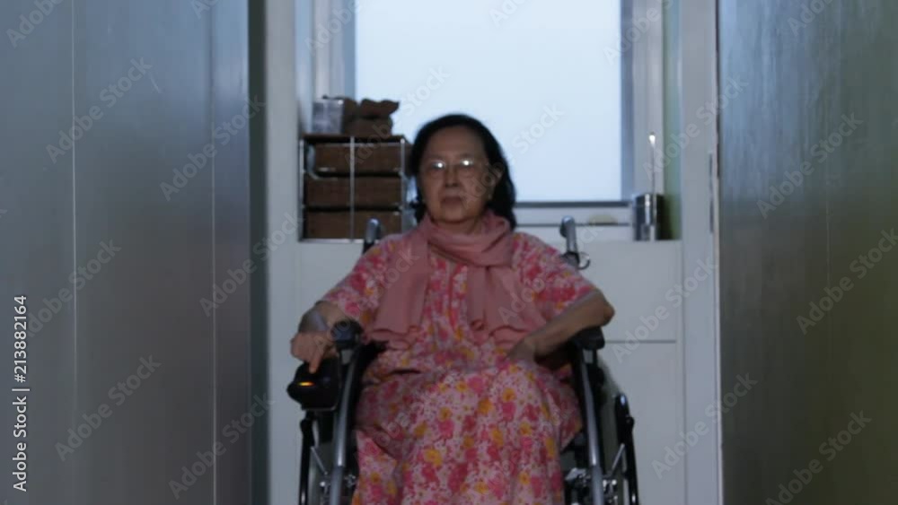 Asian senior woman moving herself by power wheelchair