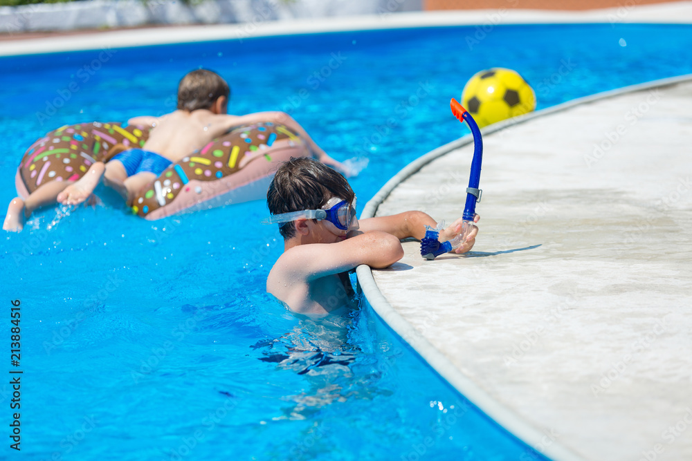 cute sporty boy swims in the pool with mask and has fun, smiles. vacation with kids, holidays, active weekends concept