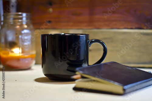 A blank black coffee mug on the work bench under candle light waiting for a idea. 