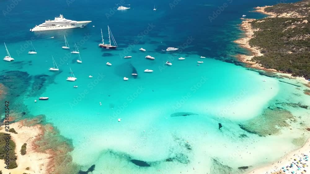 Aerial view of an emerald and transparent mediterranean sea with a white beach and some yachts. Gulf of the Great Pevero, Sardinia, Italy. Aerial view of an emerald and transparent mediterranean sea with a white beach and some yachts. Gulf of the Great Pevero, Sardinia, Italy.