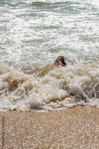 Young Girl Barely Keeping Her Head Above Water In the Foamy Ocean Surf On The Beach