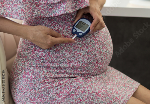 Gestational diabetes mellitus, diet of a pregnant patient with diabetes mellitus. Measurement of blood sugar level of a pregnant woman with a glucometer photo