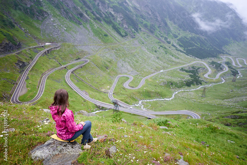 Woman sits on a stone enjoying wonderful mountain scenery. Transfagarashan Highway, the most beautiful road in Europe, Romania Transfagash , Ridge Fagaras photo