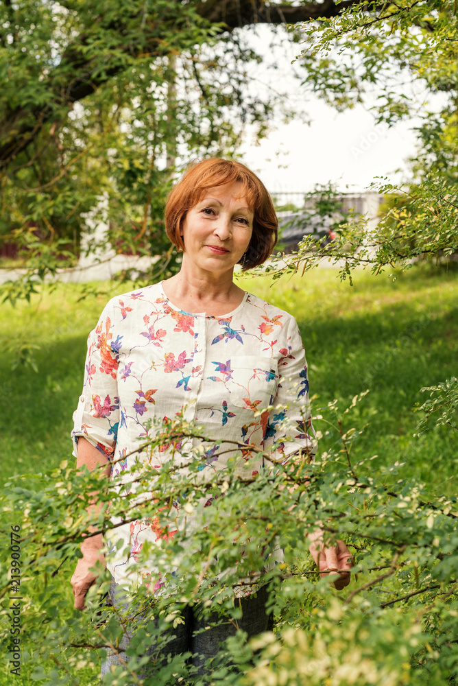 a beautiful elderly woman in flaxen clothes stands tranquilly in her green garden a beautiful elderly woman in flaxen clothes stands tranquilly in her green garden