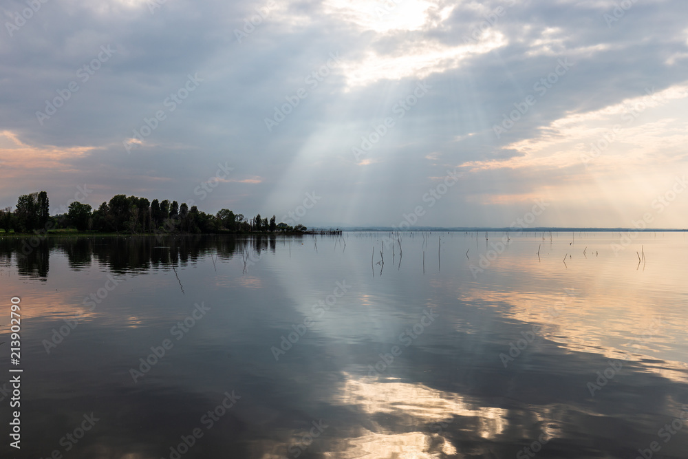 Perfectly symmetric and spectacular view of a lake, with clouds, sky and sun rays reflecting on water