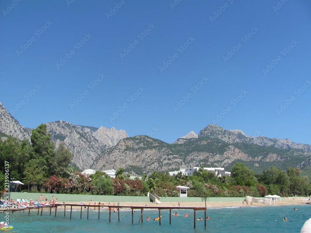 View of the beach and an empty pier from the sea, mountain ranges in the distance, beauty and peace