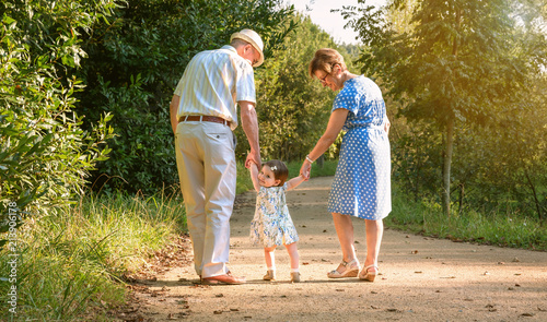 Back view of grandparents and baby grandchild walking on a nature path photo
