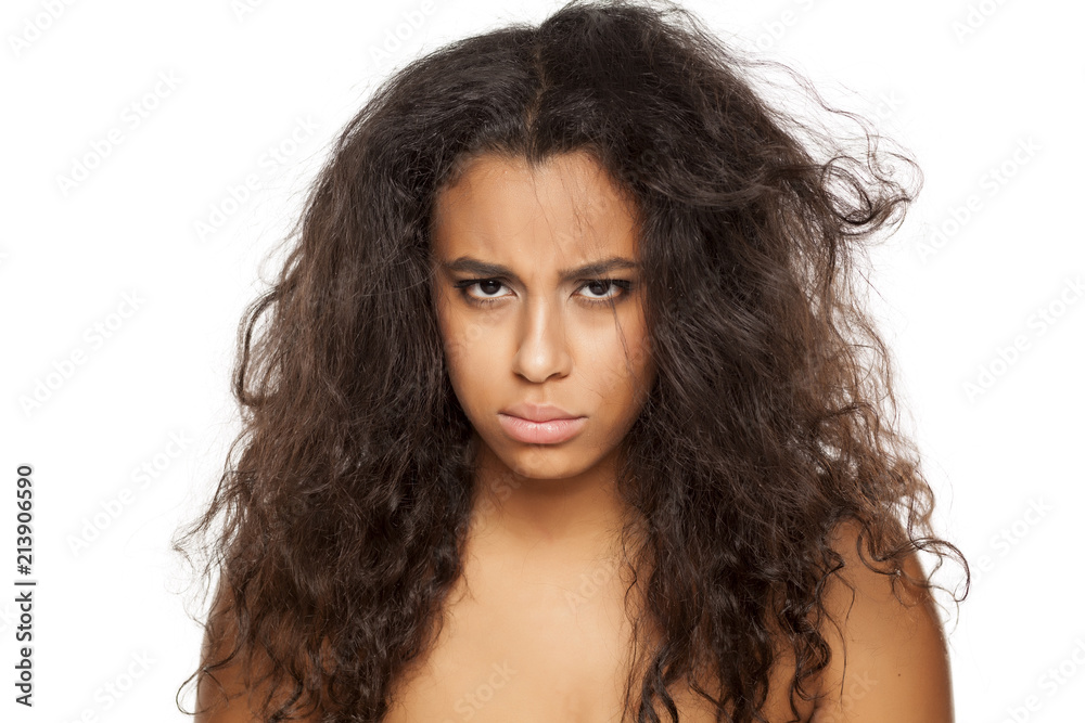portrait of a unhappy young dark-skinned woman with messy long hair on a white background portrait of a unhappy young dark-skinned woman with messy long hair on a white background