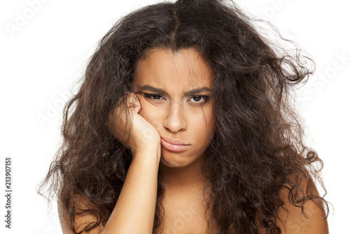 portrait of a unhappy young dark-skinned woman with messy long hair on a white background
