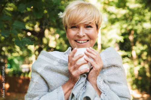 Cheerful mature woman wrapped in a blanket