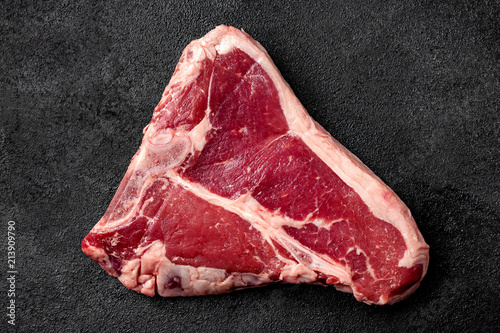 Meat raw steak lies on a black background. side view, copy space, top view