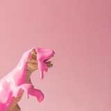 Pink paint dripping on dinosaur toy. Creative minimal concept.