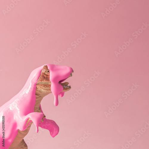 Fototapeta Różowa farba kapiąca na zabawkę dinozaura. Kreatywna minimalna koncepcja.
