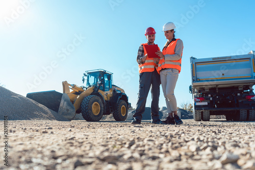 Worker and engineer on earthworks construction site planning, woman and man photo