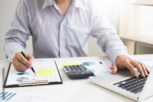 Business man working at office with laptop  tablet and graph data documents on his desk