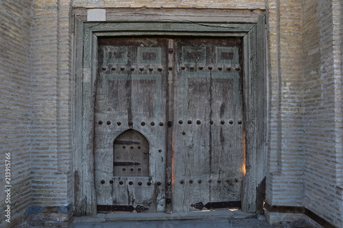 Old wooden big gate with a small door in an old brick building. Bukhara. Uzbekistan © EVGENII