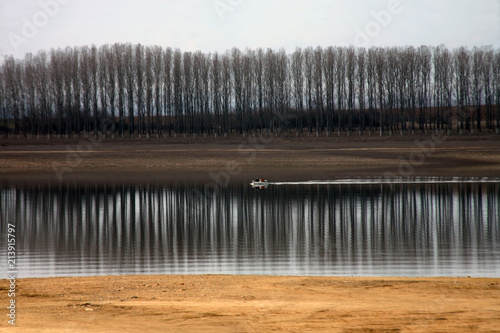 A boat in the lake with trees and their reflection in the water