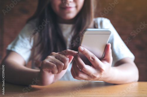 Closeup image of an asian woman holding , using and looking at smart phone