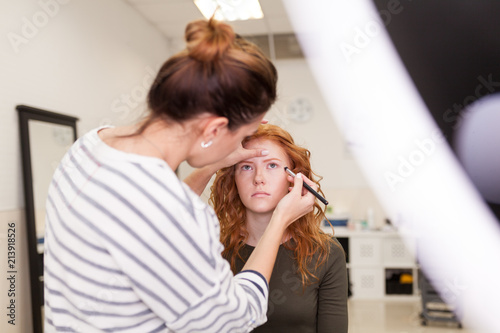 beauty salon, red-haired girl doing make-up and styling in the salon