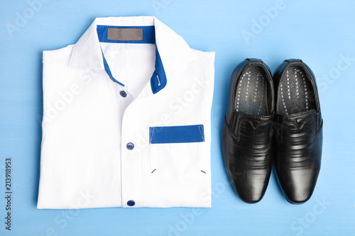 White man's shirt and black shoes on a blue background.