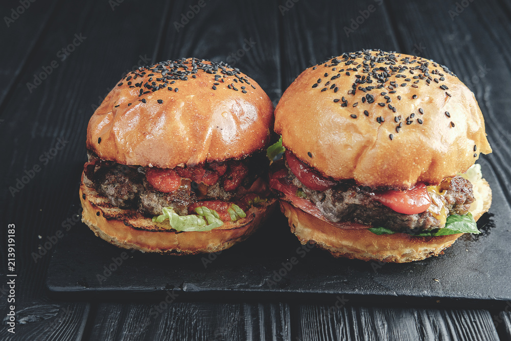 homemade juicy burgers on dark wooden board. Street food, fast food. toned image. top view