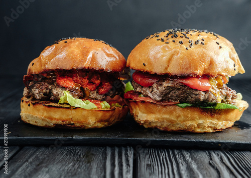 homemade juicy burgers on dark wooden board. Street food, fast food.