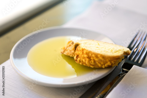 One slice of bread and olive oil in a white plate.