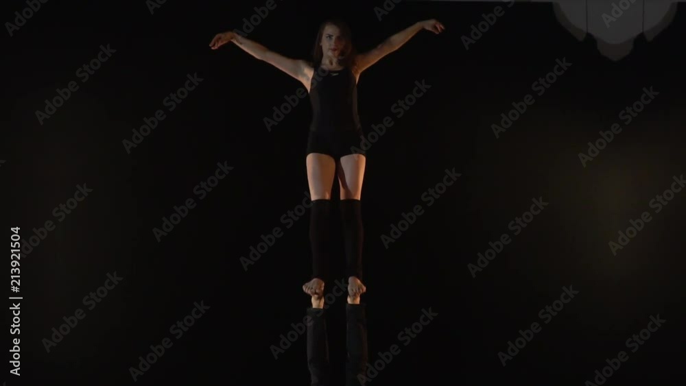 A pair of acrobats, a woman stands on the feet of a man, a woman will poke and straighten her hair A pair of acrobats, a woman stands on the feet of a man, a woman will poke and straighten her hair