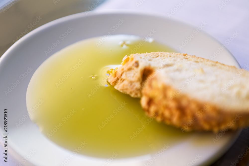 One slice of bread and olive oil in a white plate. One slice of bread and olive oil in a white plate.
