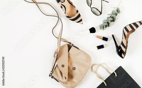 Flat lay, top view of female fashion accessories.Beige handbag, sunglasses, high heel shoes and cosmetics on white background. Copy space