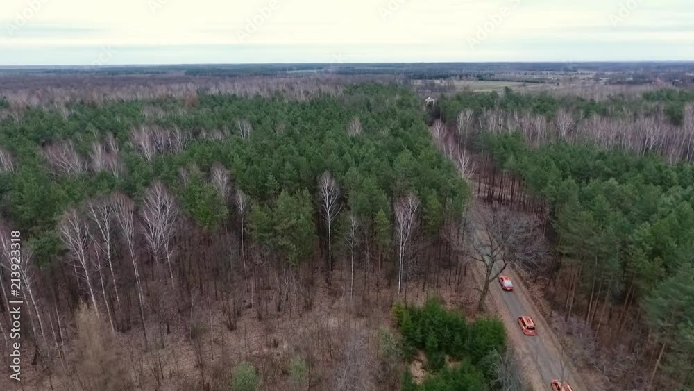 An aerial shot of orange vans driving fast on a highway.