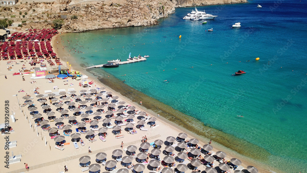 Aerial drone, bird's eye view photo of iconic and famous crowded beach of Super Paradise with sapphire clear waters, Mykonos island, Cyclades, Greece