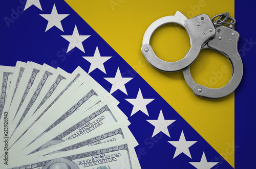 Bosnia and Herzegovina flag  with handcuffs and a bundle of dollars. The concept of illegal banking operations in US currency photo