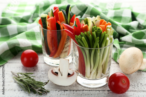 Sliced vegetables in glasses on wooden table