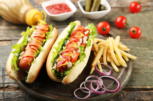 Hot dogs with vegetables and french fries on wooden table