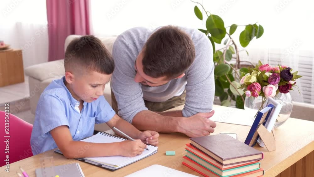 Father teaching son to write letters in copybook Father teaching son to write letters in copybook
