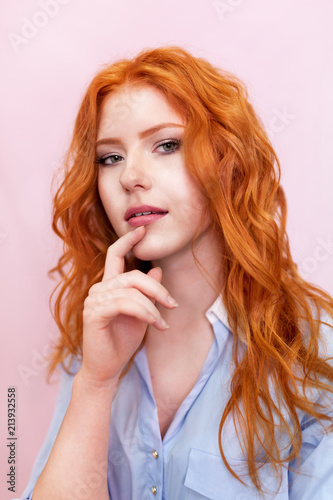 Portrait of beautiful red-haired girl on pink background