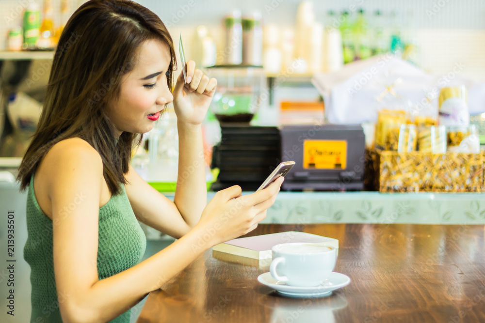 asia pretty woman are smiling face holding credit card and smartphone with coffee cup on table gray background copy space. asia pretty woman are smiling face holding credit card and smartphone with coffee cup on table gray background copy space.