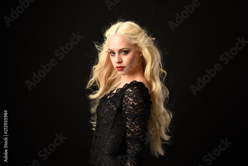 close up portrait of blonde woman wearing black lace gown. black studio background.